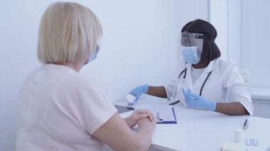 Sıcaklığı termometre ve bulaşıcı hastalıklara göre kontrol eden tıbbi pratisyen.