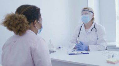 Hastane çalışanı yüz kalkanında hastayla konuşuyor, salgın viral enfeksiyon.