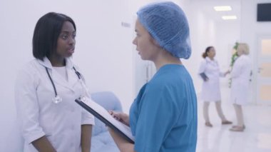 Kadın cerrah, terapist klinikte hastaların iyileşmesini tartışıyor.