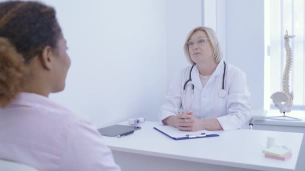 Kvalifikovaný terapeut mluvící s pacientem na klinice, lékařské péči, vyšetření — Stock video
