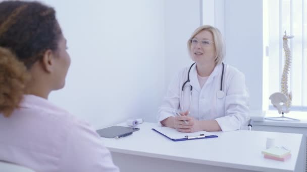 Ginecólogo femenino sonriendo a paciente en consultorio, consulta en hospital, trabajo — Vídeos de Stock