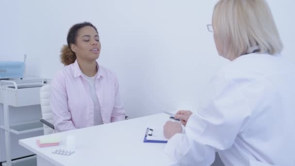 Klinikte doktoru dinleyen genç bir kadın, sağlık kontrolü, — Stok video