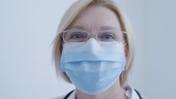 Infirmière masquée regardant à la caméra, personnel médical, prévention de la propagation du virus — Video