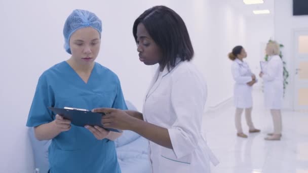 Trabajadores médicos serios hablando en el hospital, preparándose para la cirugía, atención médica — Vídeo de stock