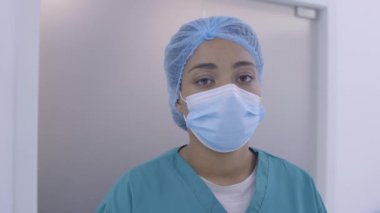 Aşırı çalışan, tıbbi maskeli Afro-Amerikan hemşire, acil serviste uzun vardiya.