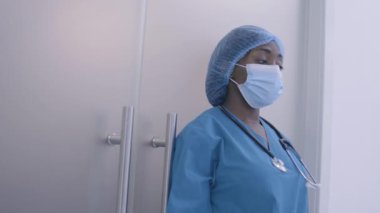 Yorgun siyah kadın doktor zor bir ameliyattan sonra alnını siliyor, yorgunluk...