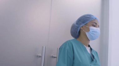 Üzgün siyah hemşire hastane koridorunda duruyor, yorgunluk çekiyor, stresli bir iş.
