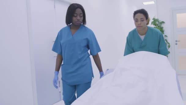 Black medical workers pushing wheel bed down hospital hall, death of patient — Stock Video