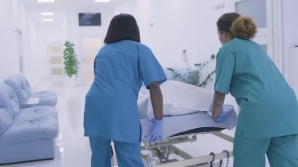 Медсестры толкают носилки с трупом пациента в морг, уровень смертности — стоковое видео