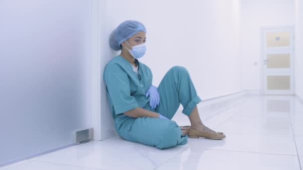 Trabalhador médico cansado sentado no chão no hospital, turno duro, surto de doença — Vídeo de Stock
