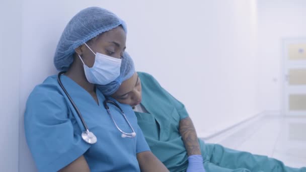 Mujeres trabajadoras médicas deprimidas sentadas en el suelo somnolientas después del turno, amistad — Vídeo de stock