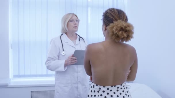 Médico serio que consulta al paciente femenino, examen de mama, prevención del cáncer — Vídeo de stock