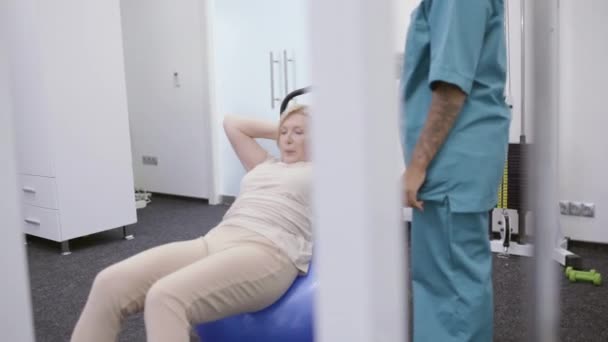 Paciente femenina haciendo ejercicio en el entrenamiento de fitball de nuevo después de una lesión fisioterapia — Vídeo de stock