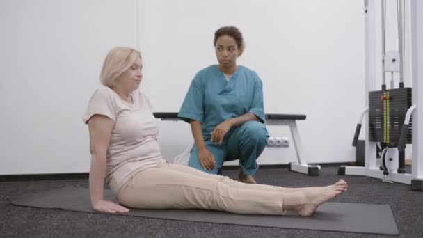 Médico afro-americano treinando mulher sênior em reabilitação profissional de ginásio — Vídeo de Stock