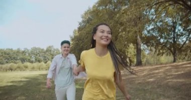 Birbirine aşık lezbiyen çift el ele tutuşup parkta mutlu mesut koşuyorlar, özgürlük.