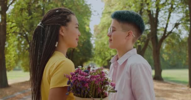 レズビアンカップルキスオン日付,花の後ろに隠れて,柔らかい関係 — ストック動画