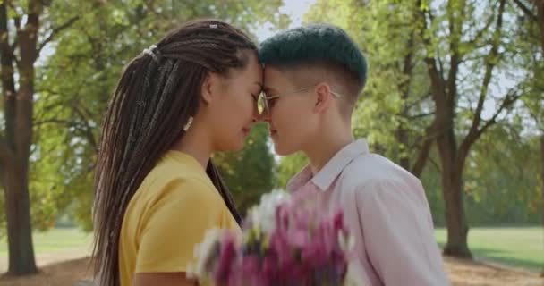 Två unga kvinnor kysser, håller blommor, samkönade förhållande, romantisk dejt — Stockvideo