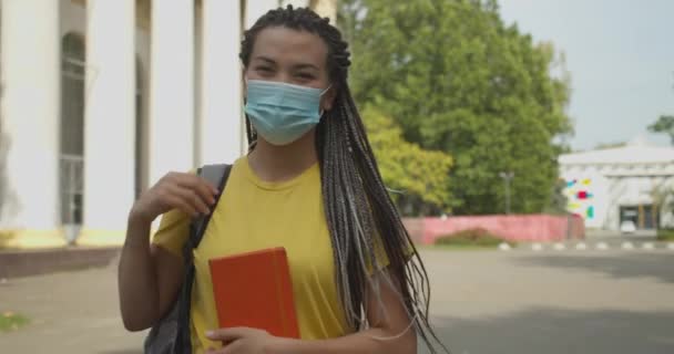 Studentin mit medizinischer Schutzmaske steht auf dem Campus, Covid-19-Pandemie — Stockvideo