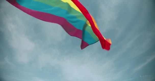 Lgbt regenboog vlag flatterend tegen rustige blauwe lucht achtergrond, gelijke rechten — Stockvideo