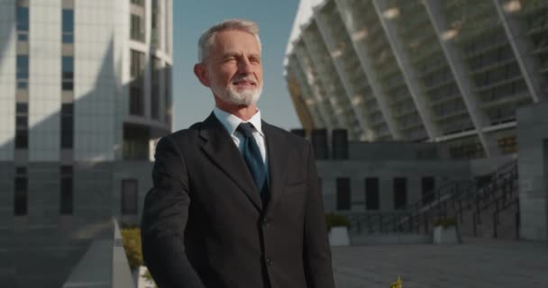Hombre de negocios sonriente parado fuera de la oficina, pensando en planes de carrera, sueño — Vídeo de stock