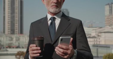Girişimci akıllı telefondan fotoğraf çekiyor, elinde bir fincan kahve, iş yeri