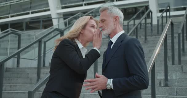 Блондинка секретарка шепоче секрет у вусі боса, колеги пліткують на роботі — стокове відео