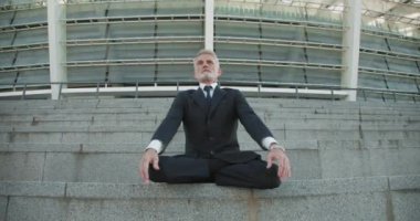 Nilüfer pozisyonunda merdivenlerde meditasyon yapan sakin bir işadamı başarıya odaklanıyor.