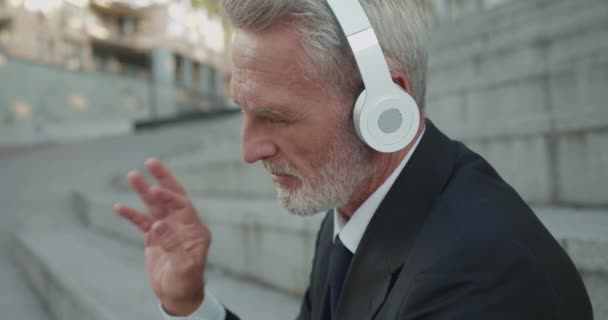 Hombre de éxito en traje de negocios disfrutando de la música en auriculares, estilo de vida relajado — Vídeos de Stock