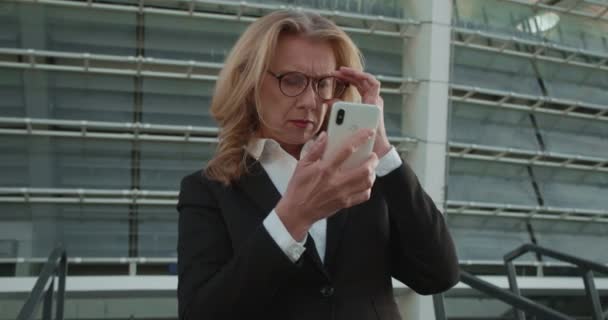 Mujer con mala vista usando anteojos para ver la pantalla del teléfono inteligente, la salud — Vídeos de Stock