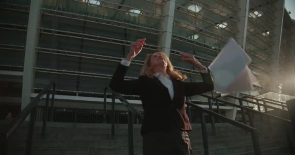 Pengusaha wanita yang bersemangat menari dan melempar kertas ke luar ruangan, merayakan kesuksesan — Stok Video