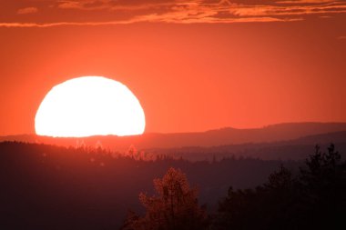 Parlak kırmızı gökyüzü ile dağların tepelerinde gün batımı.