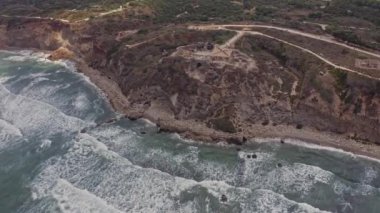 Apollonia Ulusal Parkı, İsrail 'de dalgalar ve turistler çarpışıyor. Hava aracı görüntüsü 4k