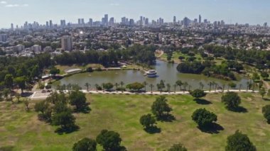 İsrail 'deki Leumi parkının üzerinde Tel Aviv iş ufuk çizgisini uzaktan gören 4k hava aracı görüntüleriyle uçuyor.