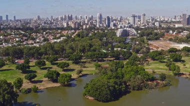 İsrail 'deki Leumi parkının üzerinde Tel Aviv iş ufuk çizgisini uzaktan gören 4k hava aracı görüntüleriyle uçuyor.