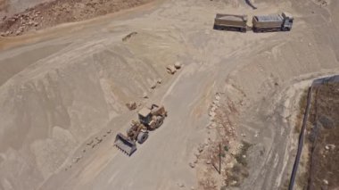 Ağır traktör inşaat alanında taş taşıyor, hava aracı görüntüsü 4k