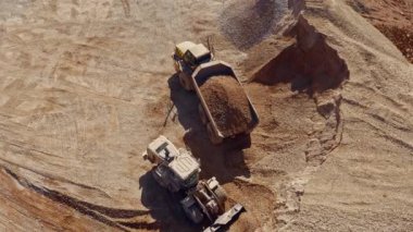 Ağır traktör inşaat alanında taş taşıyor, hava aracı görüntüsü 4k