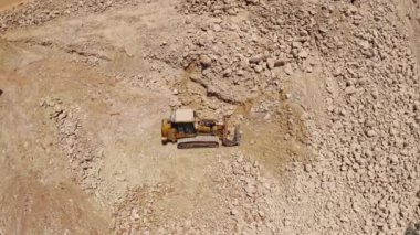 Ağır traktör inşaat alanında taş taşıyor, hava aracı görüntüsü 4k