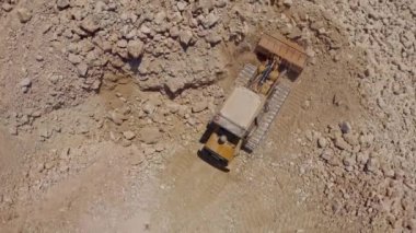 Ağır traktör inşaat alanında taş taşıyor, hava aracı görüntüsü 4k