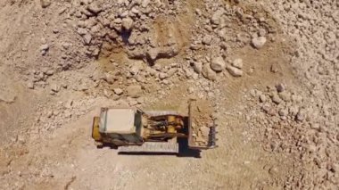 Ağır traktör inşaat alanında taş taşıyor, hava aracı görüntüsü 4k
