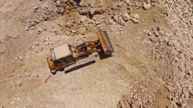 Ağır traktör inşaat alanında taş taşıyor, hava aracı görüntüsü 4k