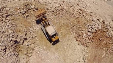 Ağır traktör inşaat alanında taş taşıyor, hava aracı görüntüsü 4k