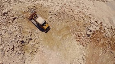 Ağır traktör inşaat alanında taş taşıyor, hava aracı görüntüsü 4k