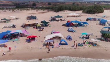 Gemi enkazı, renkli çadırları ve şemsiyeleri olan resimli bir yaz plajı.