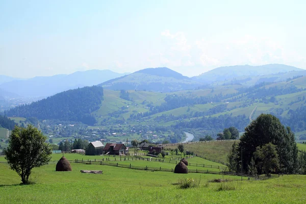 Karpatlar güzel manzaraya samanlık, mera, ahşap çit, Vadisi, nehir ve mesafe dağlarda köyünde manzaralı.