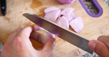 Genç adam kesme soğan ahşap tahta içinde mutfak ile A bıçak üzerinde. 