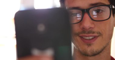 Sohbet yazarak, yansıma gözler gözlük yakın çekim smartphone kullanarak çekici genç adam.