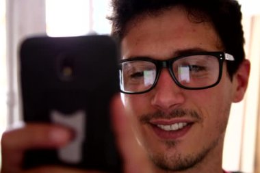Sohbet yazarak, yansıma gözler gözlük yakın çekim smartphone kullanarak çekici genç adam.