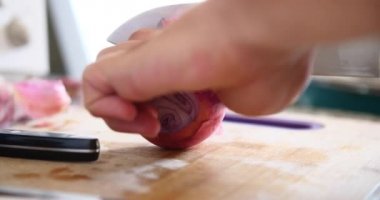 Genç adam kesme soğan ahşap tahta içinde mutfak ile A bıçak üzerinde. 