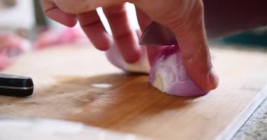 Genç adam kesme soğan ahşap tahta içinde mutfak ile A bıçak üzerinde. 