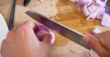 Genç adam kesme soğan ahşap tahta içinde mutfak ile A bıçak üzerinde. 